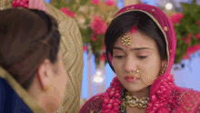 a woman with a nose ring and a veil on her head looks down at something