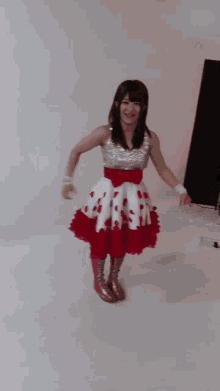 a woman in a red and white dress is standing in a room