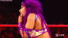 a woman with purple hair is kneeling down in a wrestling ring with a man .