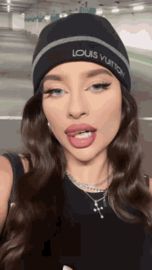 a woman wearing a beanie that says louis vuitton on it