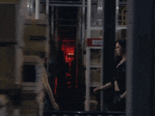 two women are standing in a dark warehouse with a red sign that says b205