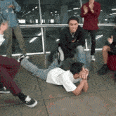 a man is laying on the floor with his legs crossed while other people watch