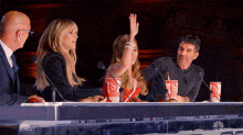a group of people are sitting at a table with coca cola cups