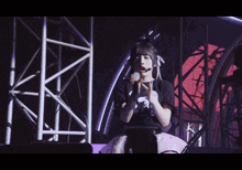 a girl wearing a black shirt that says ' a ' on it stands on a stage