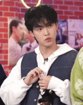 a young man in a denim vest is holding a stuffed animal in his hand