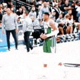 a basketball player is walking on the court with the words meet me in the back in the background .