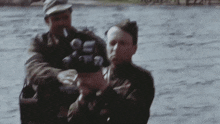 a man in a boat is holding a gun and another man is smoking a cigarette