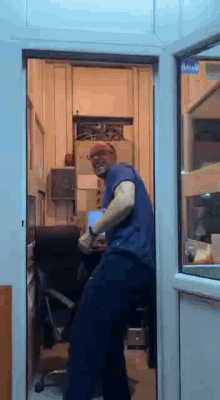 a man in a blue shirt is standing in a room with a sign on the door that says visa