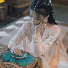 a woman in a white dress is sitting at a table looking at something