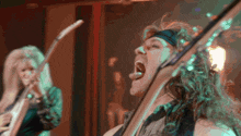 a man singing into a microphone while a woman plays a guitar