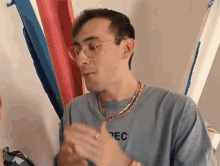 a man wearing glasses and a blue shirt that says pec on it