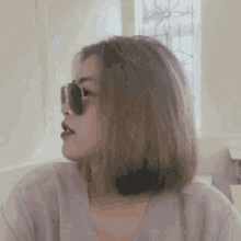 a woman wearing sunglasses and a gray shirt is looking to the side