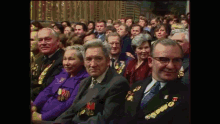 a group of people are sitting in a room and one of them has a medal on his chest that says ' m '