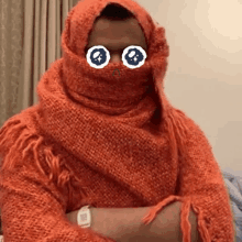 a person wearing an orange scarf around their face with a watch on their wrist