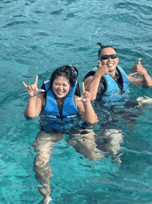 a man and a woman wearing life jackets are swimming in the ocean