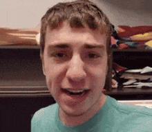 a young man in a blue shirt is making a funny face in front of a closet .