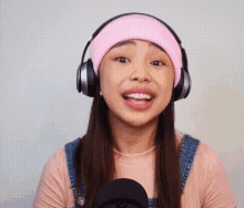 a woman wearing headphones and a pink beanie is smiling .