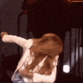 a woman is dancing on a stage while wearing a white jacket .