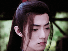 a close up of a man 's face with a ponytail