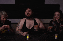 a man with a beard is sitting at a table holding a martini