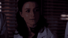a woman in a lab coat is smiling in the dark .