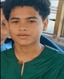 a young man in a green shirt is looking at the camera while sitting on a bus .