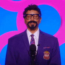 a man with a beard and glasses stands in front of a microphone with his eyes closed
