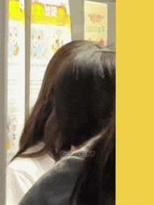a woman with long hair is sitting in front of a window and looking out .