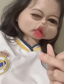 a girl wearing a real madrid jersey makes a funny face