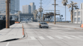 a car is driving down an empty street with palm trees