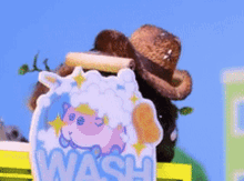 a stuffed animal wearing a cowboy hat is standing next to a sign that says wash