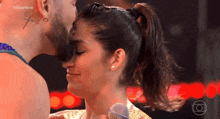 a man with a cross tattoo on his neck kisses a woman with a microphone