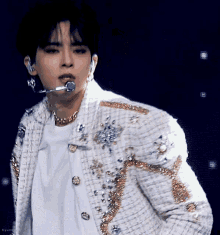 a close up of a man wearing a white jacket and a microphone in his mouth