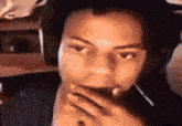 a man wearing headphones is covering his mouth with his hand while looking at the camera .