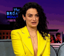 a woman wearing a yellow jacket is sitting in front of a sign that says the broadway holly