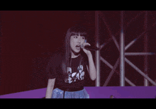 a woman singing into a microphone while wearing a black shirt that says ' aoi ' on it