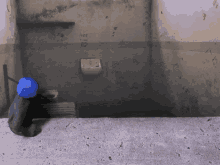 a blue ball is sitting in a dark room with graffiti on the wall that says " knee "