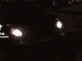 a car is driving down a street at night and the license plate says rct 12 lgn