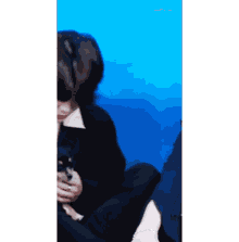 a man is sitting on the floor holding a small dog in his hands .