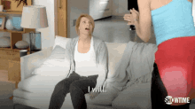 a woman sitting on a couch says i will while another woman stands behind her
