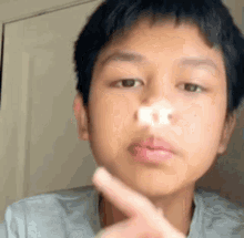 a young boy is holding his nose in front of his face .