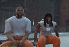 two men are sitting in front of a brick building and one has a necklace that says ice cube