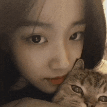 a close up of a woman holding a cat in her arms