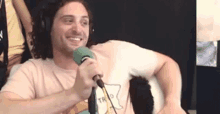 a man wearing headphones is talking into a microphone while smiling .