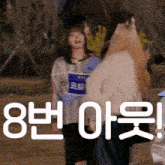 a group of girls are standing next to each other in a park with a sign that says ' 8 ' on it .