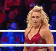 a woman in a red top is standing in a wrestling ring