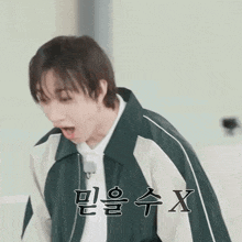 a young man wearing a green and white jacket is making a funny face .
