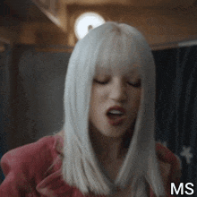 a woman with white hair is wearing a pink jacket and making a funny face