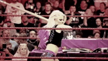 a woman is standing in a wrestling ring holding a rope .