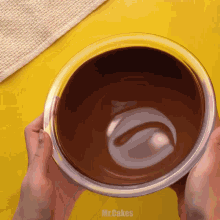 a person is holding a bowl of chocolate and the words mr.cakes are visible